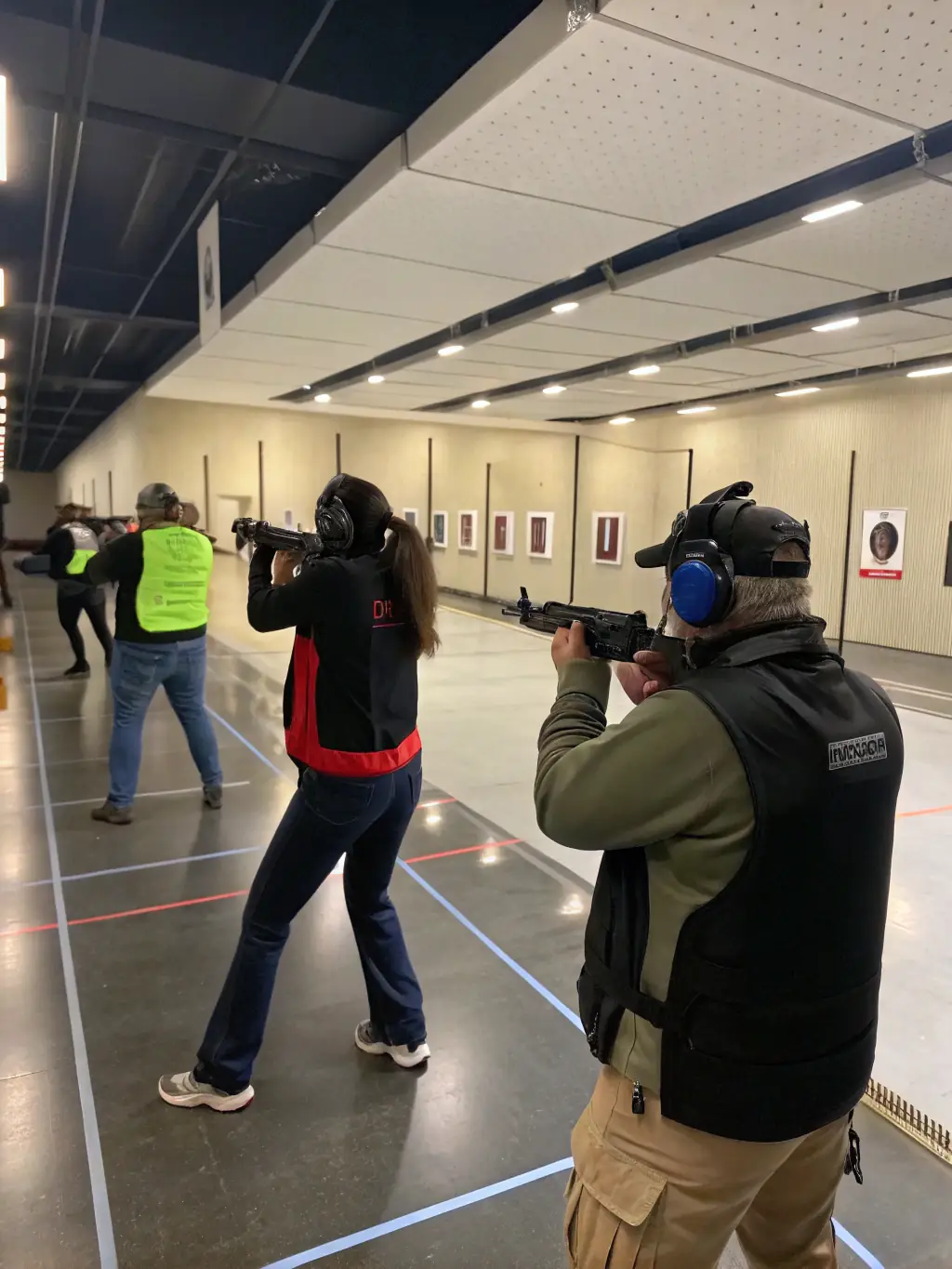 A group of beginners participating in an introductory shooting session, with instructors guiding them through the basics of firearm handling and safety.